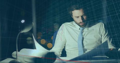 Professional man analyzing financial reports at night