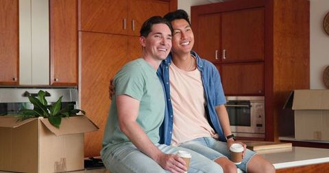 Happy Gay Couple Having Coffee in Modern Kitchen Post Moving