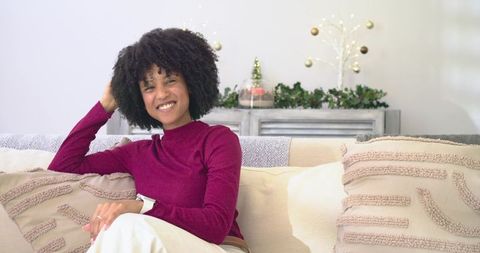African American woman smiling and relaxing on sofa in cozy holiday living room