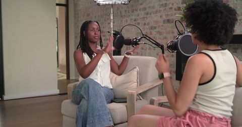 African american cohosts conversing in modern home podcast studio with pro microphones