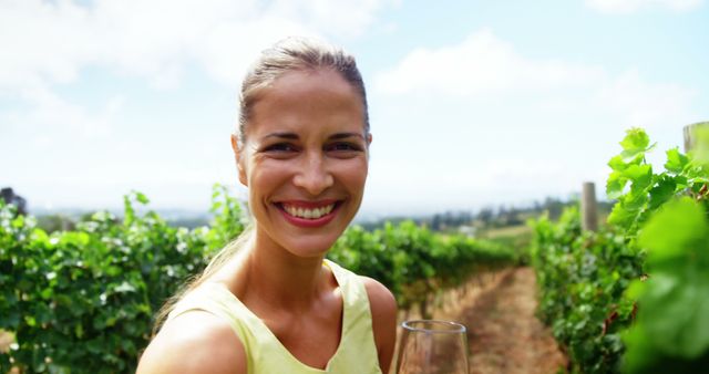 Pretty woman smiling and smelling red wine on a vineyard
