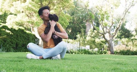 Man embracing puppy on sunny lawn capturing connection outdoors