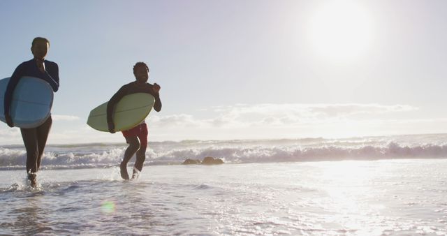 African american couple running with surfboards on the beach - Download Free Stock Photos Pikwizard.com