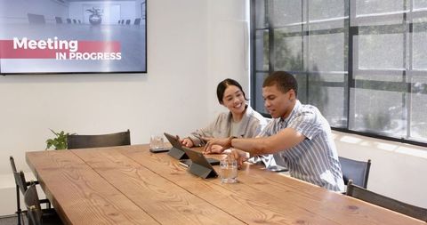 Multiracial Colleagues Collaborating on Tablets in Modern Meeting Room