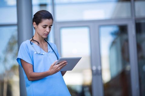 Female Healthcare Professional Using Tablet at Clinic Entrance