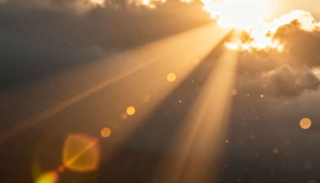 Golden sunbeams streaming through storm clouds over ridge with bokeh and lens flare