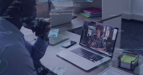 Businessman watching remote video call on laptop with digital data overlays in office