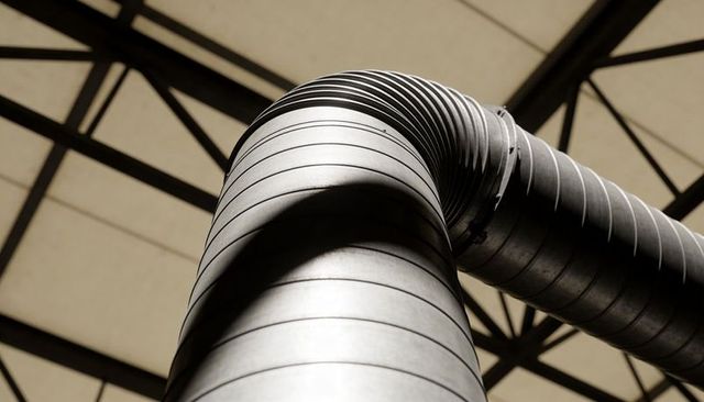 Rising curved industrial ventilation duct highlighting steel trusses and geometric detail