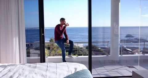 Man enjoying coffee on coastal balcony with scenic ocean view