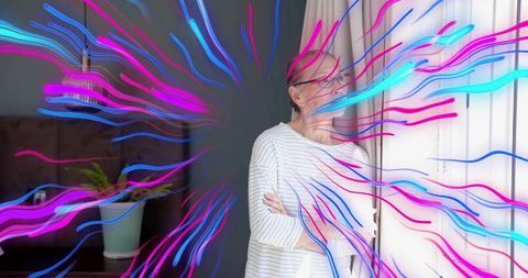 Senior chinese woman standing by window, gazing through curtains with neon art overlay