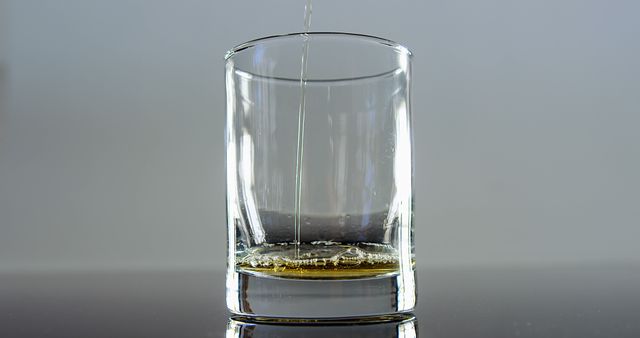 Pouring Liquid into Short Glass on Reflective Surface - Download Free Stock Images Pikwizard.com