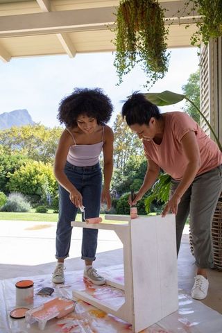 Mother and Daughter Painting Wooden Table on Patio