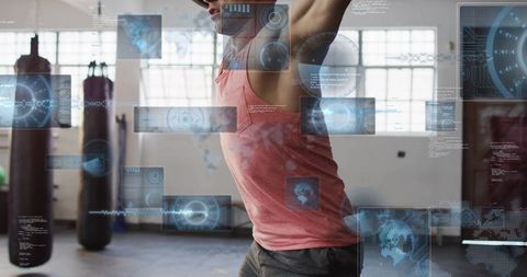 Male athlete lifting arms in gym with futuristic digital hud overlays and training tech