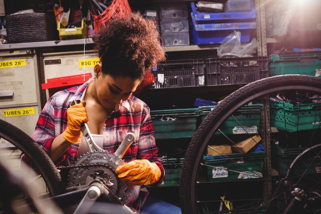 Bicycle mechanic focusing on repairing the gear system with tools in a busy workshop environment. This image can be used for websites, articles, and advertisements related to bike repairs, maintenance services, skilled trades, and mechanical workshops.