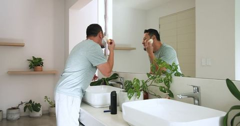 Man applying shaving cream in modern minimalist bathroom