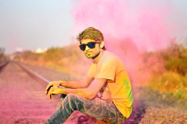 Young Man Celebrating Holi with Colorful Powder on Railroad Tracks - Download Free Stock Photos Pikwizard.com