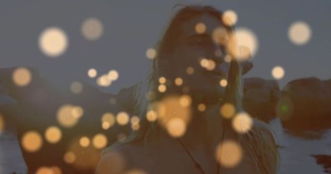 Shirtless Man with Dumbbells on Rocky Shore at Dusk with Artistic Bokeh