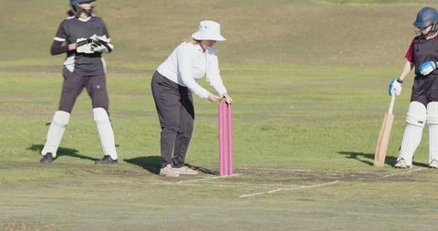 Female Cricketers Preparing Field and Stumps for Match