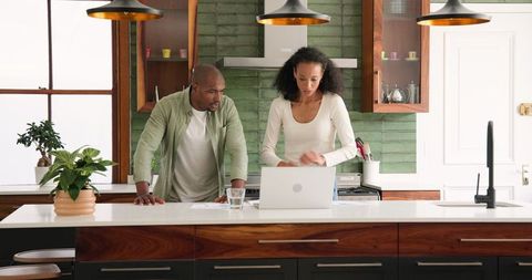 Diverse Couple Cooking together in Modern Kitchen with Laptop Assistance