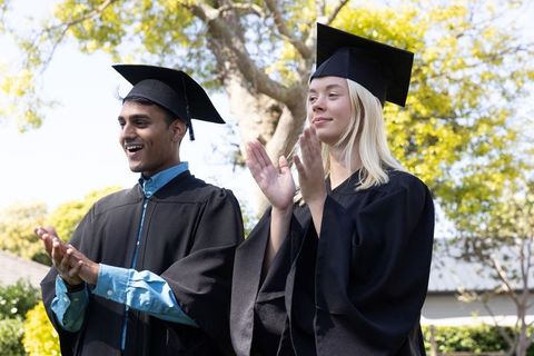 Diverse Graduates Applauding Outdoor Commencement Ceremony