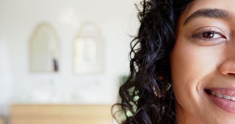 Smiling Woman Leaning on Bathroom Vanity Near Arched Mirrors