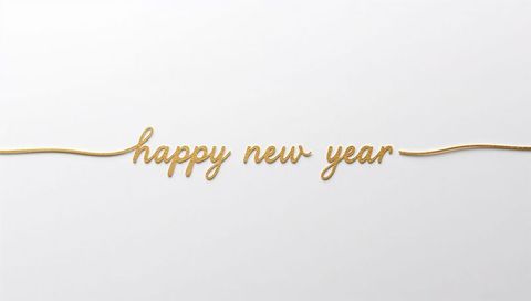 Minimalist gold cursive happy new year script on white backdrop with thin metallic cord