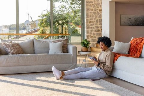 African american man relaxing on floor using tablet in sunlit contemporary living room