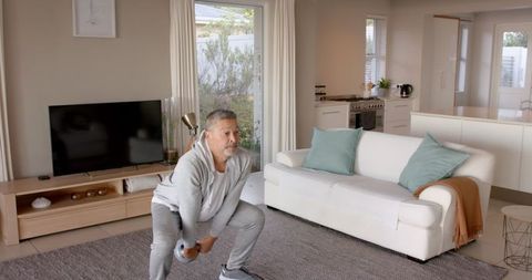Senior Man Exercising with Kettlebell in Bright Living Room
