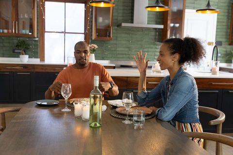 Cozy candlelit dinner for diverse couple sharing conversation and wine in modern kitchen