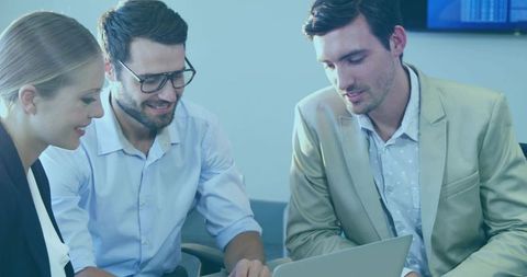 Three professionals collaborating and reviewing laptop in modern corporate meeting room