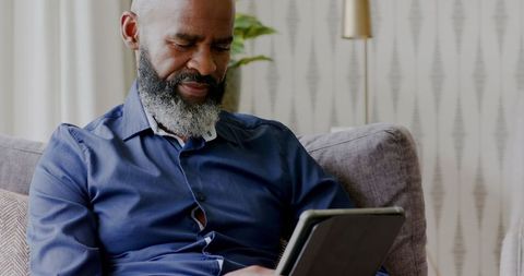Mature Man Engaged in Tablet Use on Comfortable Sofa