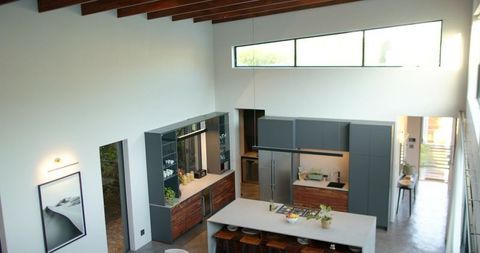 Modern minimalist kitchen island anchoring bright open-plan living with clerestory windows