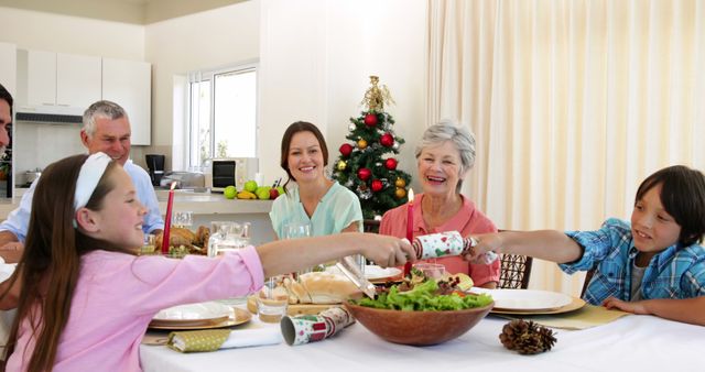 Family Celebrating Christmas Dinner with Smiles and Cracker Pulling - Download Free Stock Images Pikwizard.com