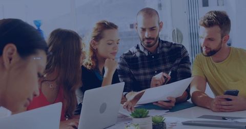 Creative Team Reviewing Documents and Collaborating Around Sunlit Office Table
