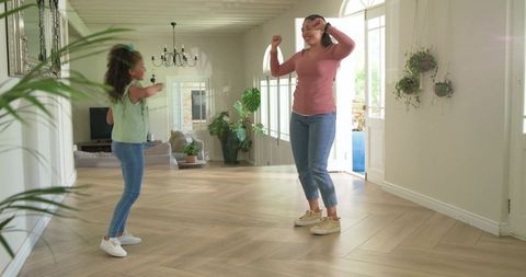 Mother and daughter dancing on herringbone floor in bright airy home