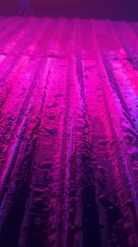Moving Camera Revealing Wet Corrugated Metal Roof with Magenta Reflections Vertical Video