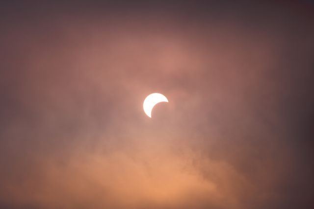 Partial Solar Eclipse Behind Atmospheric Clouds at Sunset - Download Free Stock Photos Pikwizard.com