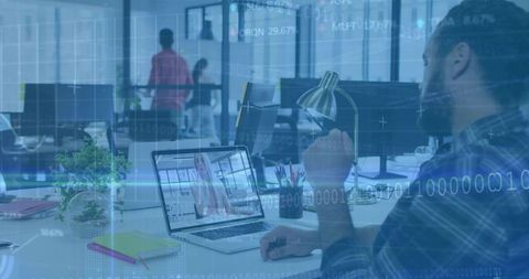 Bearded man working on laptop video call in open-plan office with data overlay