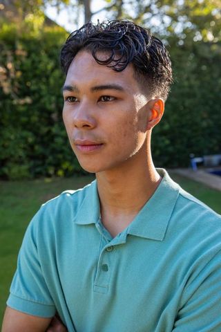 Young man in green shirt enjoying sunny backyard