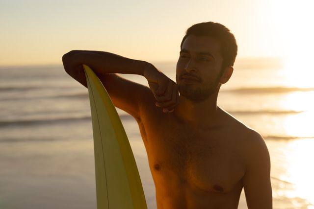 Young man standing with surfboard on the beach