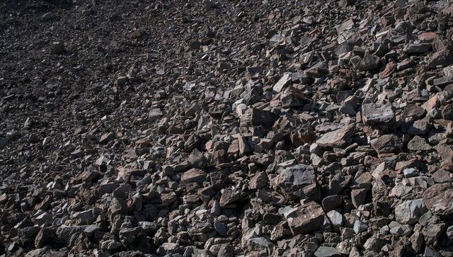 Angular talus slope with sunlit boulders and scree on rugged arid hillside, rocky texture