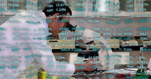 Scientist examining sample in lab microscope with overlaid stock market data