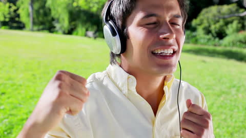 Happy Man Listening to Music and Singing in Park