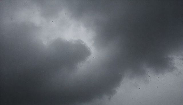 Swirling cumulonimbus cloud revealing bright inner pocket and falling specks