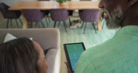 Senior couple using smart home tablet in cozy open-plan living room