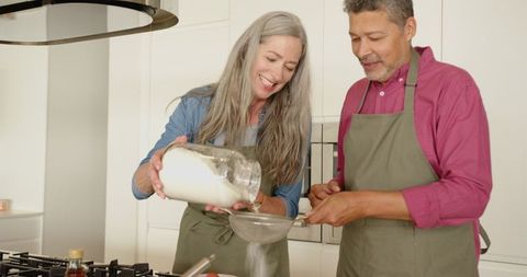Senior Couple Together Sifting Flour in Modern Kitchen