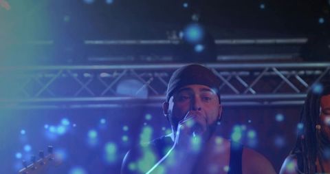 Bearded lead vocalist performing under blue bokeh lights with handheld microphone