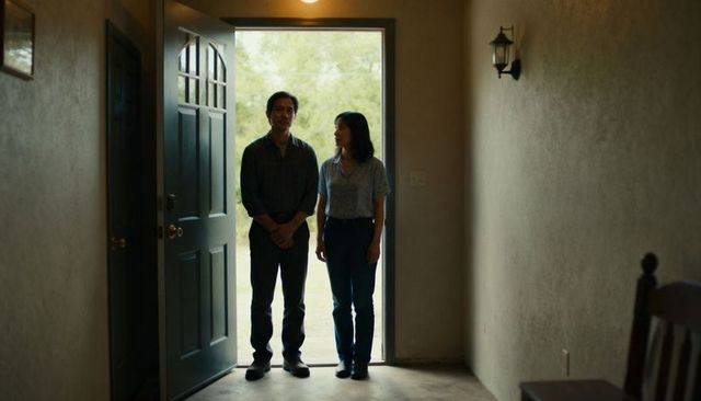 Couple standing at open front door looking out to green yard in quiet entryway
