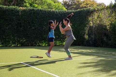 Mom and Daughter High-Fiving on Tennis Court Embracing Active Lifestyle