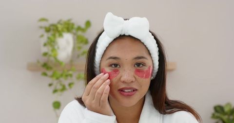 Woman adjusting skincare patches in minimalist spa environment
